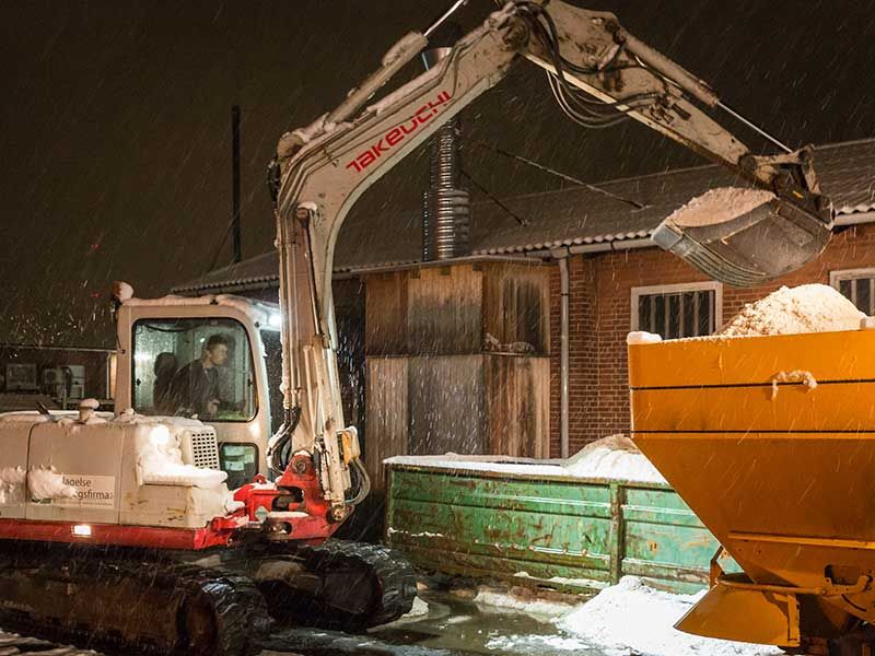 Gravemaskine der læsser salt i en container tidligt om morgen, så der kan blive udført saltning.